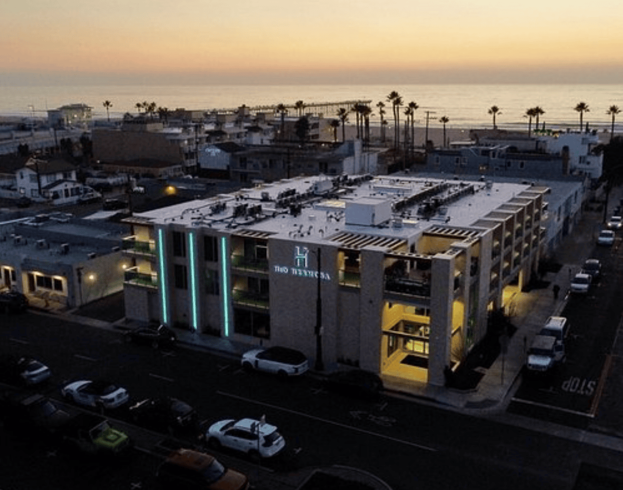 Aerial view at dusk of the H2O Hermosa hotel on Hermosa Avenue, one block from the Strand, with the Hermosa Beach Pier and the Pacific behind it