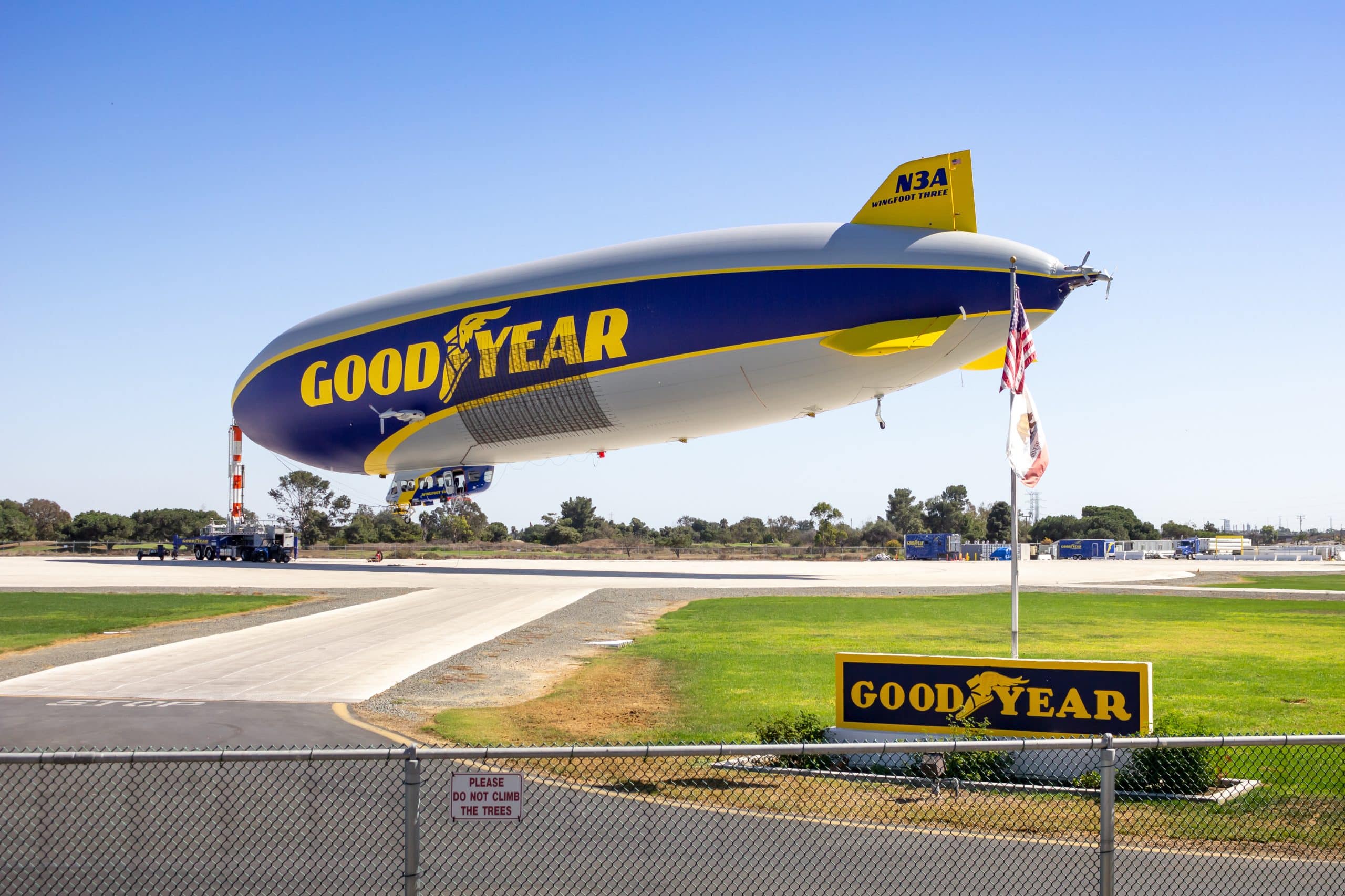 The Goodyear blimp moored on the ground beside a Goodyear sign