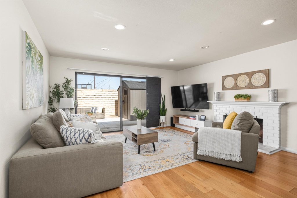 Living room in a South Bay home with a sectional sofa, white painted brick fireplace and sliding doors to a rear patio