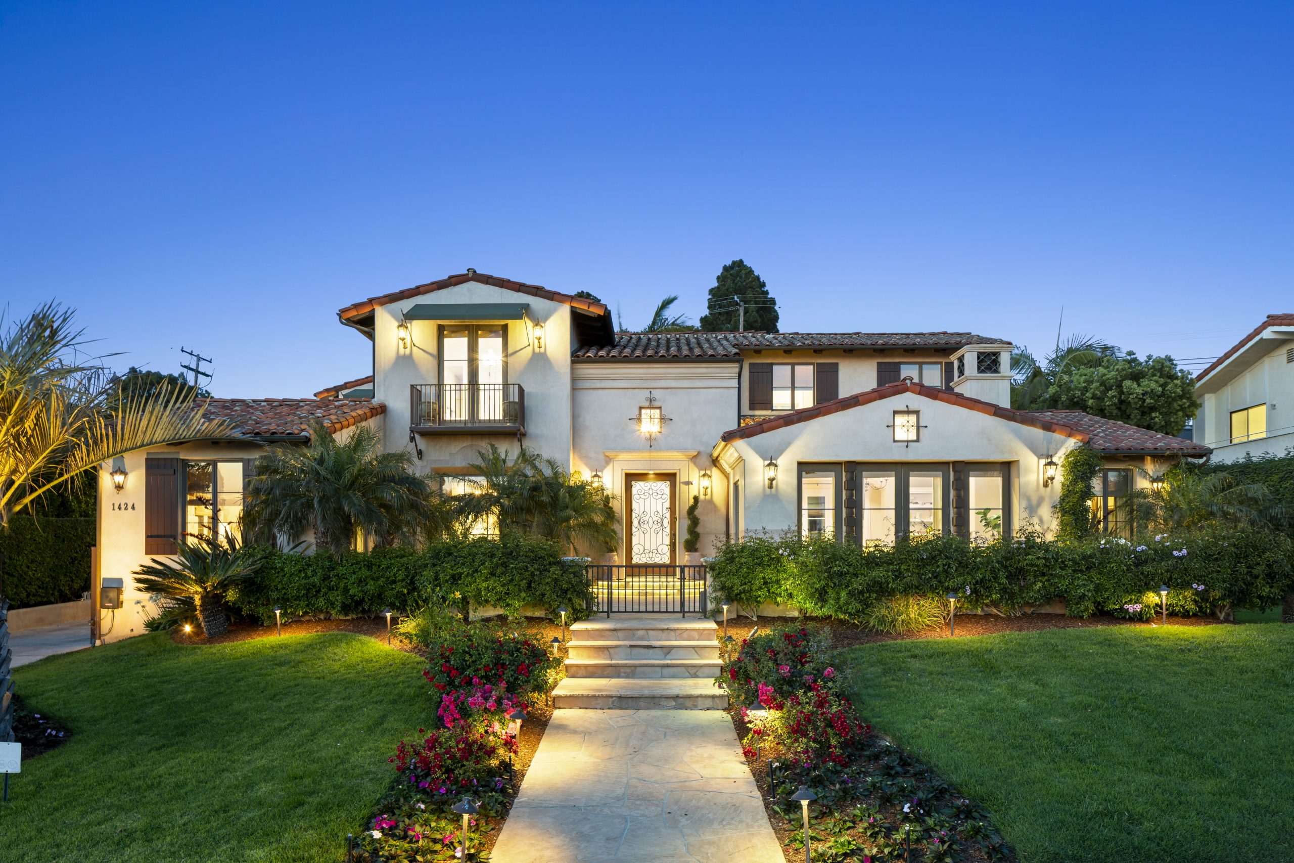 Large Mediterranean style estate at twilight with a lit entry drive