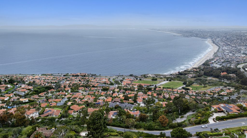 Elevated view from a hillside over a coastal town and a long curving bay