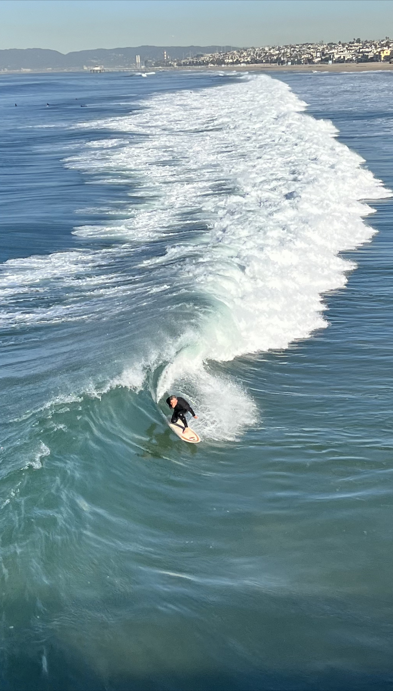 Surfer riding inside the barrel of a wave beside the Hermosa Beach Pier in the South Bay of Los Angeles