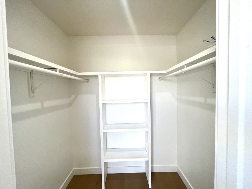 Walk-in closet in Unit A at 624 W. 38th Street, San Pedro, with hanging rods and shelves on two walls and a column of open shelves in the middle.